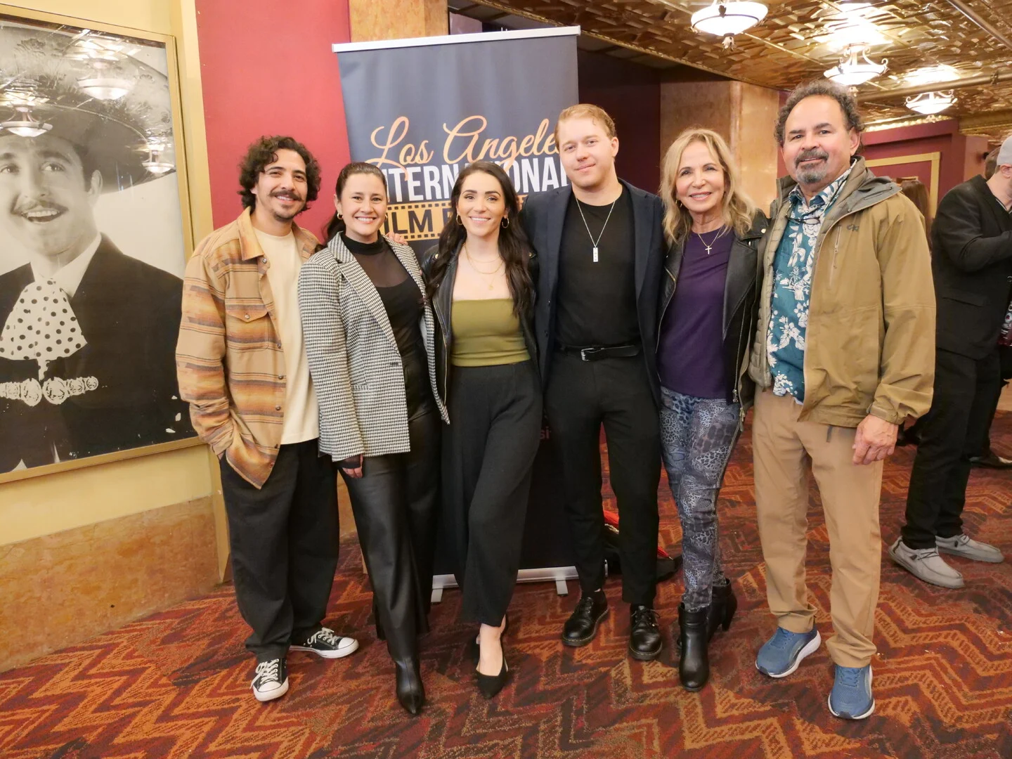 A group of six festival guests together beside the LAIFF banner