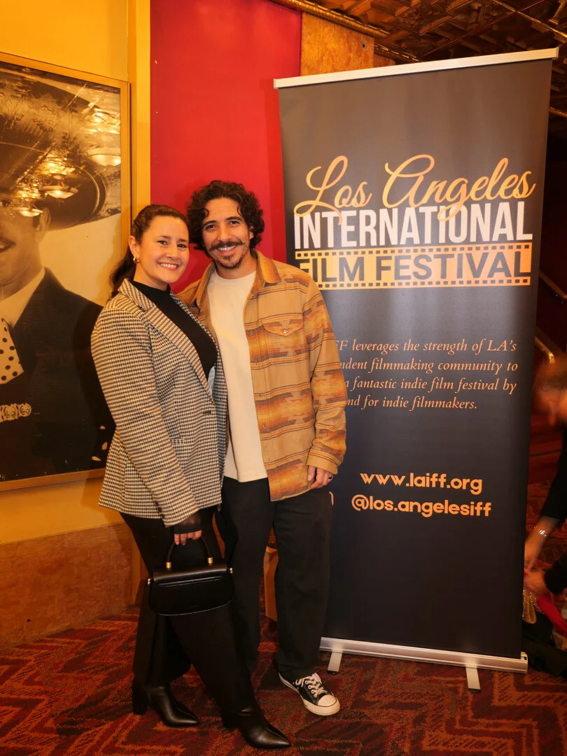 Two festival guests beside the LAIFF banner